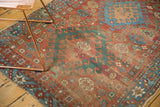 Antique Caucasian rug detail with red field, geometric hook motifs, blue border, and worn selvages.