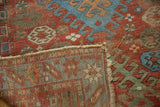 Antique Caucasian rug's hand-knotted foundation, worn selvage, and geometric red, blue, green pattern.