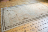 Vintage Oushak rug corner with distressed beige pile and rams horn geometric border.
