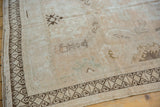 Corner of distressed Oushak rug, showing dark chocolate rams horn border and even pile wear.