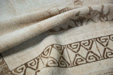 Textured beige pile and dark brown geometric rams horn border on distressed Oushak rug.