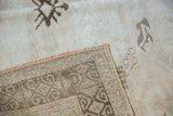 Distressed beige pile with faint foundation and geometric hand-knotted reverse of an Oushak rug.