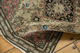 Curled corner of an antique Farahan Sarouk rug, showing low pile, blush, blue, and charcoal floral design.