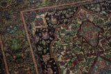 Intricate black field of an antique Kashan rug, with emerald, lavender, and pink silk florals.