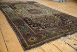 Angled view of an antique silk Mohtashem Kashan rug, intricate floral patterns, deep gem tones.