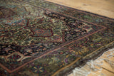Finely woven antique silk Kashan rug border, displaying aubergine, green, and gold floral motifs.