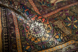 Close-up of fine silk pile showcasing varied gem tones and intricate floral pattern on antique Kashan rug.