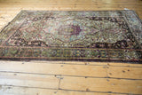 Ornate green and aubergine border on the corner of an antique silk Mohtashem Kashan rug.