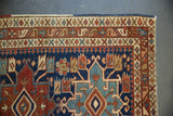 Heriz rug corner: intricate geometric borders and Karaja motif in navy, wine red, sky blue.