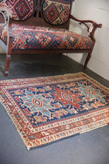 Antique Heriz rug corner with geometric motifs, pawn border, navy, sky blue, and red.