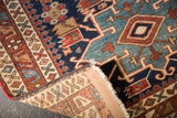 Antique Heriz rug's hand-knotted construction, polychrome selvage, and geometric navy, red, beige patterns.