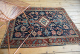 Antique Heriz rug's diamond medallion, broad floral palmettes, and deep blue, red, ivory tones.
