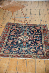 Secured fringe of antique Heriz rug, showing navy, wine red, and ivory floral patterns.