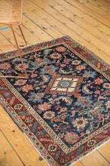 Antique Heriz rug's even-worn pile showing navy, red floral palmettes and secured fringe.