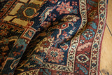 Folded antique Persian Heriz rug showing restored wine red selvage, detailed ivory and powder blue border.