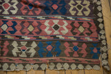 Heavily tattered end of an antique Persian Kilim carpet, showing crab design motifs in madder red, ivory, brown.