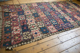 Heavily tattered corner of an antique Persian Kilim showcasing madder red and ivory crab design.