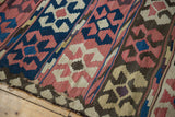 Hand-woven Antique Persian Kilim detail: madder red, blue, ivory crab motifs, tattered edge.