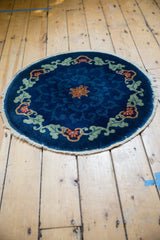 Chinese Art Deco round rug border with cobalt blue field, green scrolling vines, and orange floral arabesques; fringe detail.