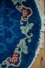 Art Deco rug close-up: cobalt blue field, green vine, pinkish flower, and tattered fringe.