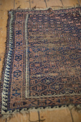 Worn navy and coffee brown geometric trellis and starburst patterns on this antique Belouch rug.