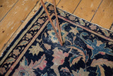 Antique Chinese rug corner with Persian stylized navy, beige, pink floral motifs. Visible pile wear and tatter, early 20th century.