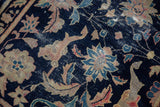 Detail of antique Chinese rug: worn navy field, beige palmettes, aqua vinery, exposed foundation.