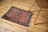 Vintage Sarouk rug corner with tattered fringe, low pile, and blush floral vinery.