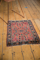 Low pile, tattered fringe, and navy border on a vintage Sarouk rug with blush vinery.