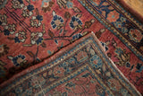 Corner detail of a vintage Sarouk rug, showing low pile, tightly woven edge, and field of faded blossoms.