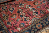 Vintage Sarouk rug's low pile, delicate floral vinery in deep blush and navy blue.