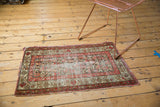 Antique Hamadan rug detail: worn field revealing foundation, floral vine motif border.