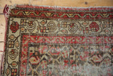 Hand knotted antique Hamadan rug detail showing mostly even wear to knot heads, red, brown, ivory motifs.