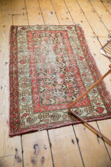 Tattered end of the antique Hamadan rug, with red, ivory, brown meandering vine border.