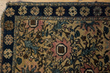 Dog-eared corner of vintage Farahan Sarouk rug, with navy floral border and blush motif.