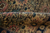 Folded vintage Farahan Sarouk rug detail: hand-knotted pile, navy, ivory, blush trellis pattern.