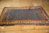 Antique Hamadan rug's meandering vine border with beige and orange tones and worn, tattered end.