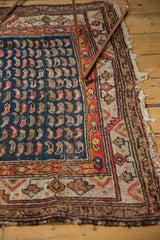 Antique Hamadan rug detail: geometric vine border, navy Mahi Mahi field, and tattered edge.
