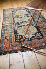 Tattered end of vintage Hamadan rug, showing navy blue, rust, and ivory border.