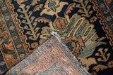 Folded corner of vintage Hamadan rug, revealing worn floral pile and detailed hand-knotted back.