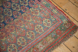 Tattered corner of antique West Persian rug, showing madder root red, green, and sky blue traditional border.