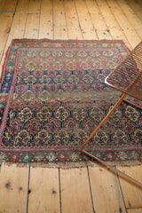 Detail of antique West Persian rug: repeating medallions, visible foundation, and frayed edges.