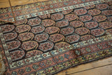Corner of antique Northwest Persian runner, charcoal boteh motifs, copper borders, and tattered fringe.