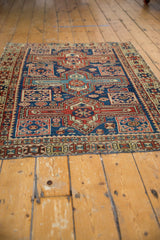 Antique Caucasian rug's detailed geometric border in madder red, navy blue, with a tattered edge.