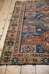 Antique Caucasian rug side with geometric border in saffron, navy, and madder red, showing wear.
