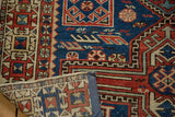 Antique Caucasian rug's folded corner reveals navy, madder red geometric patterns and knotted foundation.