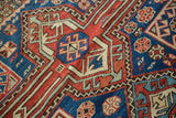 Detail of antique Caucasian rug’s geometric pattern with madder red, navy blue, and saffron pile.