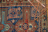 Antique Caucasian rug's detailed geometric pattern, navy blue, madder root red, and saffron, showing knot wear.