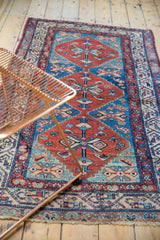 Malayer runner's geometric border showing abrash and low pile in red, blue, and ivory tones.