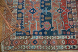 Antique Serapi rug corner showcasing unusual asymmetric border patterns and fringed end.
